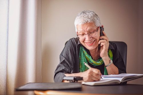 senior-woman-on-phone-sitting-at-table